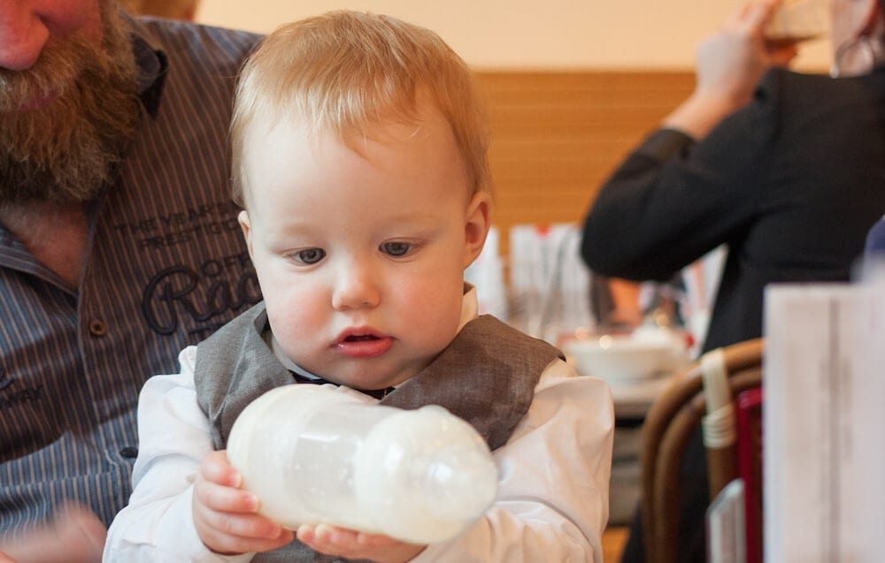 Kind untersucht Babyflasche | familiert.de